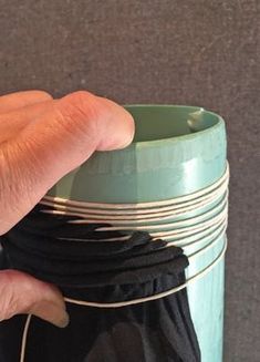 a hand is holding onto a stack of black and white cups with strings attached to them