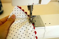 someone is using a sewing machine to sew on a polka dot fabric with a red and white dotted cloth