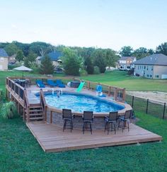 an above ground pool surrounded by wooden decking and patio furniture with chairs around it