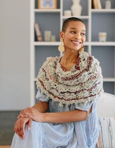 a woman sitting on top of a couch wearing a shawl and smiling at the camera