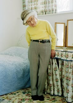 an old woman standing in front of a bed