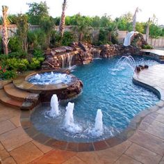 an outdoor swimming pool with water features and waterfall in the center, surrounded by palm trees