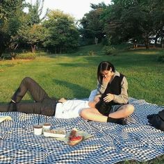 two people sitting on a blanket in the grass