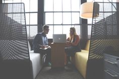 two people sitting at a table with laptops