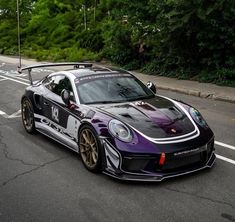 a black and purple sports car driving down the street