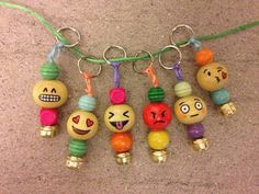 several different colored beads with faces hanging from a string on a carpeted floor in front of a wall