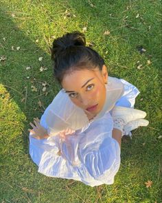 a woman laying in the grass with her hands on her chest and looking up at the camera