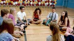 a group of young people sitting on top of a basketball court