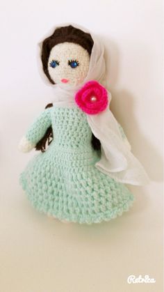 a crocheted doll with a pink flower in her hair, wearing a green dress