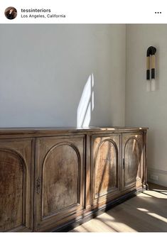 a large wooden cabinet sitting on top of a hard wood floor next to a white wall