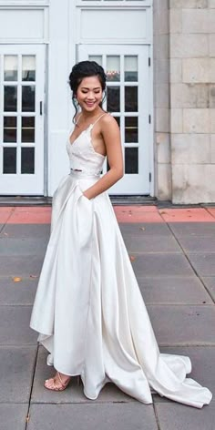 a woman standing in front of a white door wearing a wedding dress with a bow at the waist