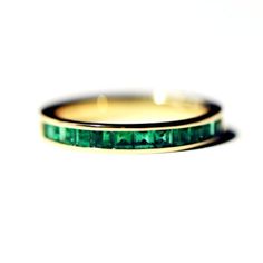 two gold rings with emerald colored stones on them