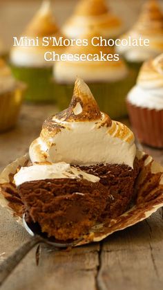 cupcakes with white frosting and brown icing on top are sitting on a wooden table