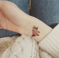 a woman's hand with a rose tattoo on her left wrist and the other arm