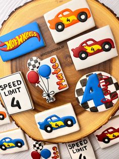 decorated cookies with cars and balloons are on a wooden platter for a birthday party