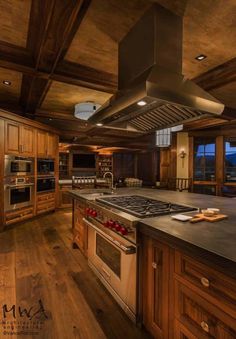 a large kitchen with an island and stove top oven in the center, surrounded by wooden cabinets