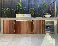 a modern outdoor kitchen with wood and stainless steel grill, sink, and dishwasher