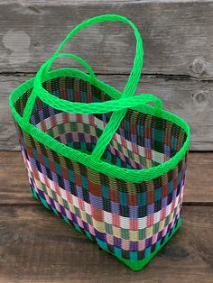 two baskets with green handles sitting on top of a wooden table