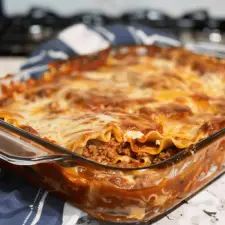 a casserole dish with meat and cheese in it on a blue and white table cloth