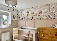 a baby's room with a crib, dresser and wallpaper on the walls