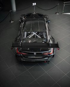 the rear end of a black sports car parked in a garage with its hood up