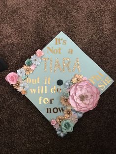 a blue graduation cap with flowers on it that says, it's not a tia but it will be for now