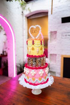 a multi layer cake sitting on top of a wooden table next to a pink archway