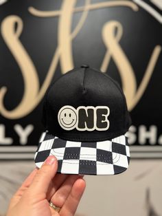 a person holding up a black and white hat with the word one printed on it