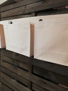 three white bags hanging on the side of a wooden wall