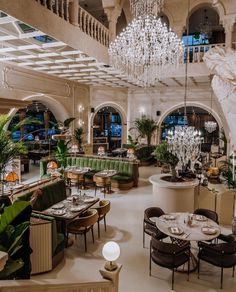 a restaurant with chandeliers hanging from the ceiling and tables set up for dinner