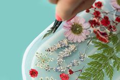 a person is painting flowers on a plate