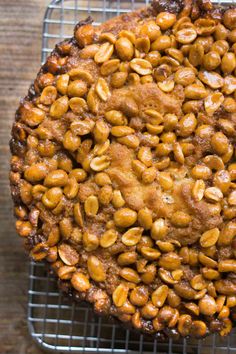 a close up of a cake on a cooling rack with nuts in the top half