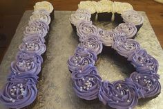 there is a cake shaped like the letter e on top of a silver plate with white and purple frosting