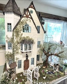 a doll house with furniture and trees in the front yard, next to a window