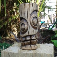 a carved wooden tiki head sitting on top of a tree stump in the garden