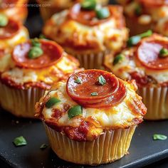 some cupcakes with pepperoni and cheese on top are sitting on a black plate