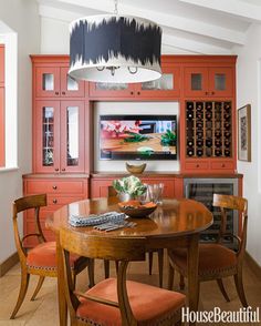 an image of a dining room with red cabinets and orange chairs on the sidelines