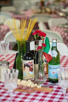 there are many bottles and glasses on the table with red checkered tables cloths