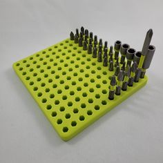 a green peg board with many holes and screws on it's sides, sitting on a white surface