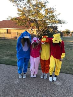 three children in winnie the pooh costumes standing next to each other on a sidewalk