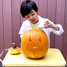 a young boy carving a pumpkin for halloween