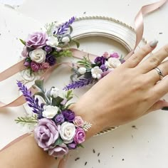 a woman's hand on top of a cake decorated with purple and white flowers