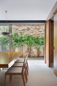 a wooden table sitting in front of a window next to a wall with plants on it