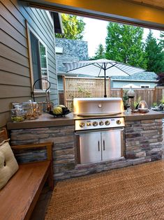 an outdoor kitchen with grill and seating area