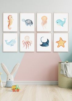 a child's room with pink walls and four paintings on the wall, including sea animals