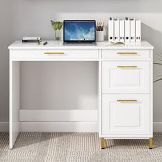 a white desk topped with a laptop computer next to books and a potted plant