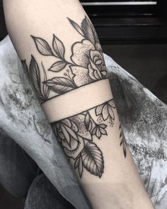 a woman's arm with flowers on it and a ribbon around the wrist tattoo