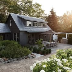 a black house with white flowers in the front yard