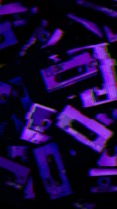 a pile of purple and black cassettes on top of each other in the dark