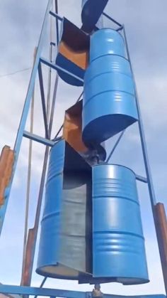 there are many blue barrels on the top of this tower that is being used as a playground